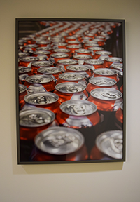 Cans of soda run along the conveyor belt in this image by photographer Fred Greaves, one of many on display at NorthBay's new Occ Health building.